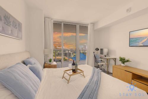 a bedroom with a bed and a desk and a window at Balcony with Infinite Views - Poolside Comfort in Hallandale Beach