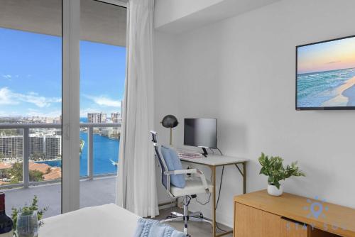 a bedroom with a desk with a computer and a window at Balcony with Infinite Views - Poolside Comfort in Hallandale Beach