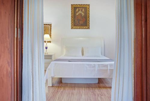 彼得罗波利斯Lazer Completo - Piscina - Churrasqueira - Vista的卧室配有一张白色床,墙上挂着一幅画