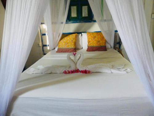 a bedroom with a white bed with white curtains at One More Wave Surf House Uluwatu in Uluwatu