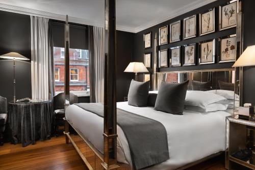a bedroom with a large white bed with black walls at The Franklin London - Starhotels Collezione in London