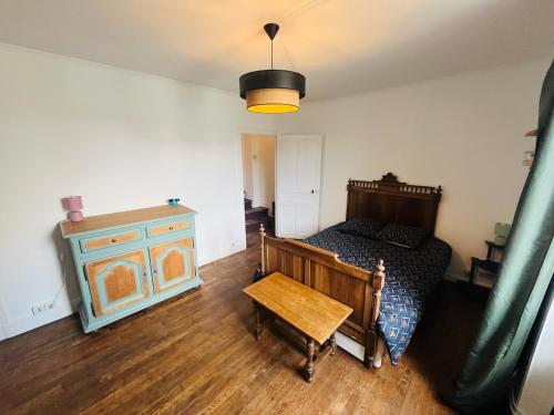 a bedroom with a bed and a wooden table at maison cosy avec jardin in Suèvres