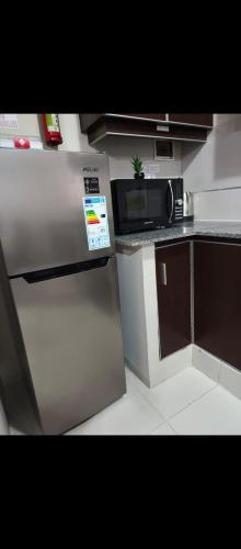 a small kitchen with a refrigerator and a microwave at Departamento práctico y funcional in Cochabamba