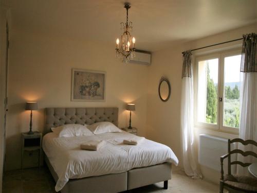 1 dormitorio con 1 cama con lámpara de araña y ventana en Mas in Eygalières with Heated Pool, en Eygalières