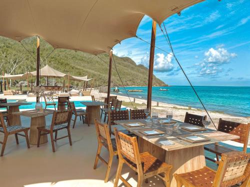 a restaurant on the beach with tables and chairs at Tenuta Chatham Bay in Union Island