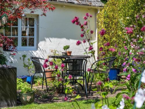 a table and chairs in a garden with flowers at Mill Barn in Askham