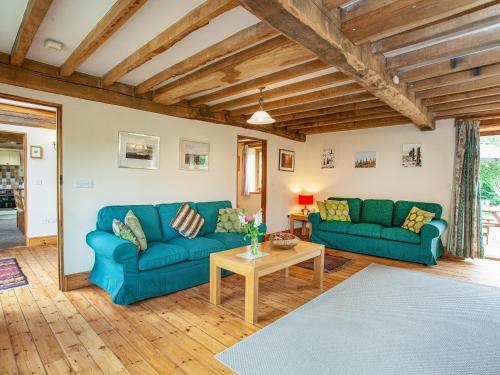 a living room with blue couches and a table at Pondmead in Monk Okehampton
