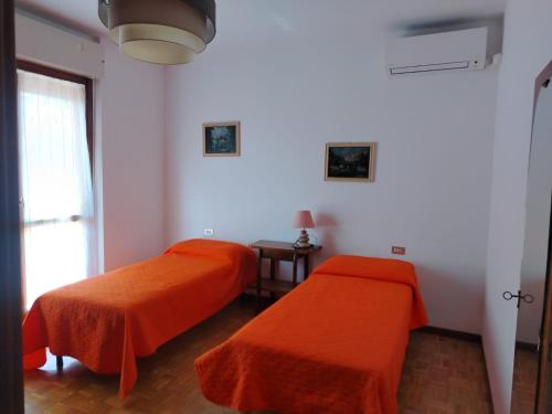 two orange beds in a room with a window at Casa Maria in Curno