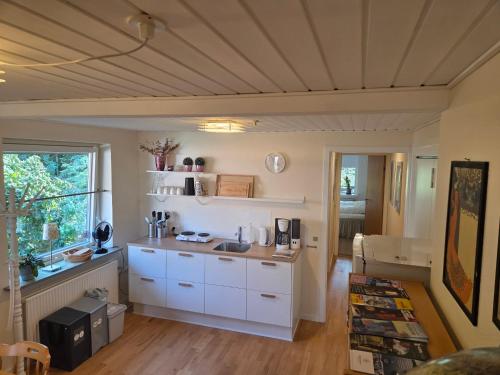 a kitchen with white cabinets and a window at Oasen - hyggelig lejlighed in Videbæk
