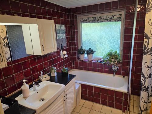 a bathroom with a tub and a sink and a window at Oasen - hyggelig lejlighed in Videbæk