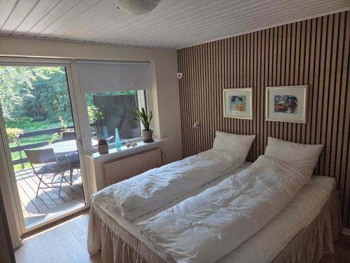 a large bed in a room with a balcony at Oasen - hyggelig lejlighed in Videbæk