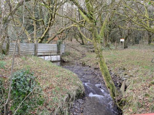 a park bench next to a stream with a stream at The Mill in Tregaron
