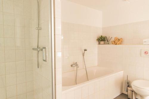 a white bathroom with a tub and a toilet at Dutchen Park Weideduyn in Schoorl