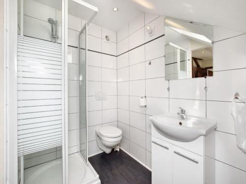 a white bathroom with a toilet and a sink at Fine group house with sauna garden in Chiny
