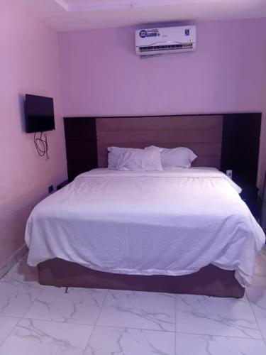 Un dormitorio con una cama grande con un edredón blanco. en Onicron Guest Inn, en Moniya