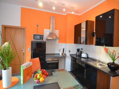 a kitchen with orange walls and a table with a bowl of fruit at Charming Forest Escape for Two in Langewiesen