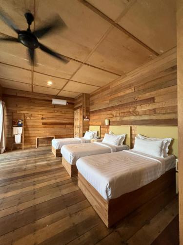 two beds in a room with wooden walls at Sisipan Island Resort in Semporna