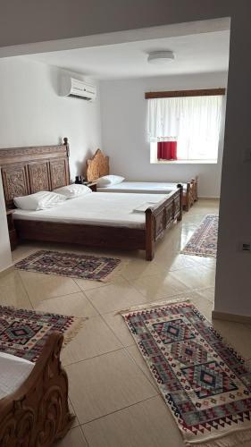 two beds in a bedroom with rugs on the floor at Guri Guesthouse in Gjirokastër