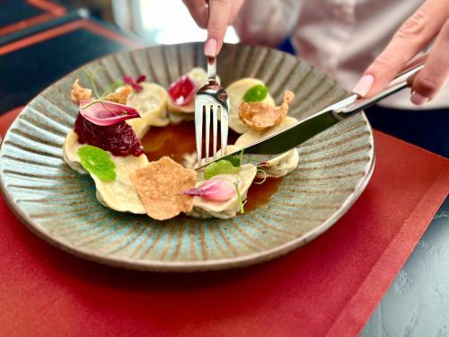 a person cutting a plate of food with a fork and knife at Hotel Ferreus Modern Art Deco in Kraków