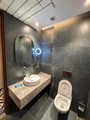 a bathroom with a toilet and a sink and a mirror at The Blu in Ghaziabad
