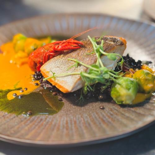 a plate of food with a piece of fish and vegetables at Hotel Ferreus Modern Art Deco in Kraków