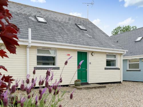 a white house with a green door and flowers at Jubileum Lodge Uk27999 in Watton