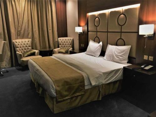 una camera d'albergo con un grande letto e due sedie di Belvilla Alhamra Vivid Plaza Hotel a Gedda
