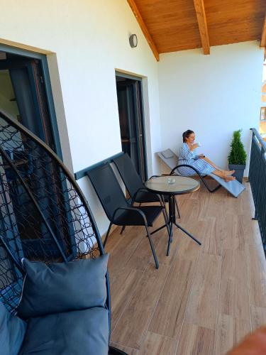 a person sitting on a balcony with a table and chairs at Apartmani Višegradski pogled in Višegrad