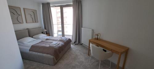 a bedroom with a bed and a desk and a window at Pinea Apartments in Pobierowo