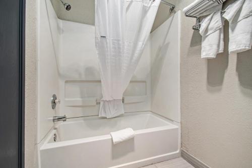 a bathroom with a tub and a shower with towels at Days Inn & Suites by Wyndham Mt Pleasant in Mount Pleasant