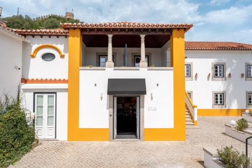 a white and yellow building with a doorway at &Tales Hotel Óbidos in Óbidos