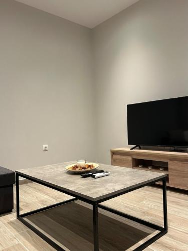 a living room with a table and a tv at MtsHome in Áyios Spirídhon