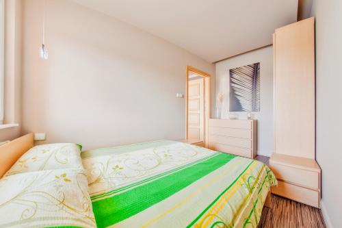 a bedroom with a bed with a green and yellow blanket at Bursztynowe Osiedle Jantar, Sun & Snow in Jantar