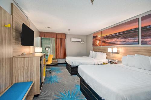 a hotel room with two beds and a flat screen tv at Days Inn & Suites by Wyndham Mt Pleasant in Mount Pleasant