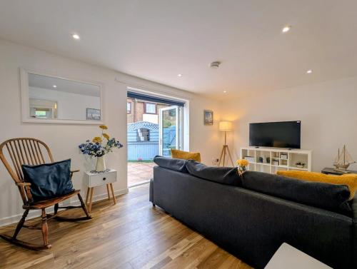 a living room with a black couch and a television at Cottage by historical dockyard in Portsmouth