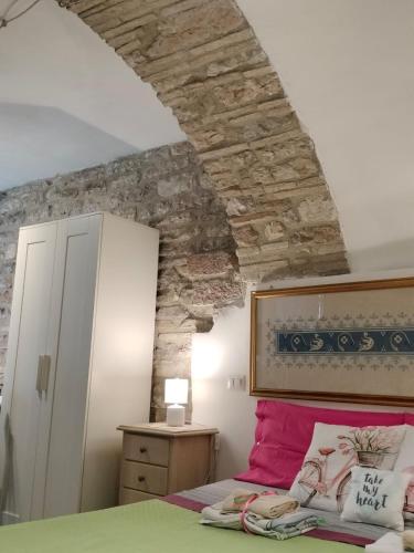 a bedroom with a bed and a stone wall at Apartments Aurora Delle Rose in Assisi