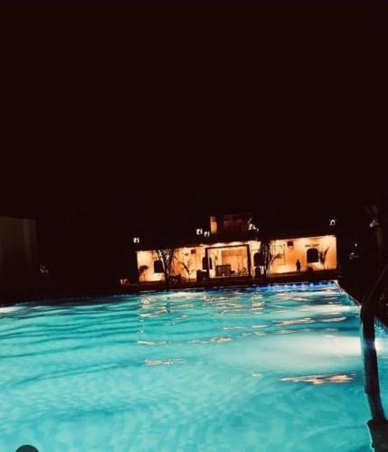 a swimming pool at night with a house in the background at Apex resort in Pushkar