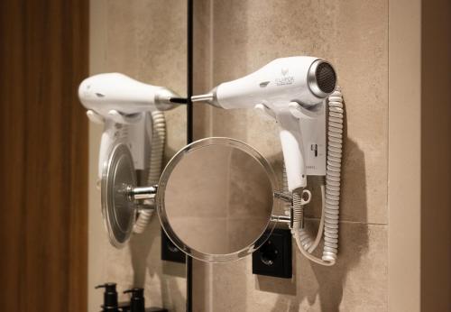 a hair dryer hanging on a wall with a mirror at NH Collection Amsterdam Flower Market in Amsterdam