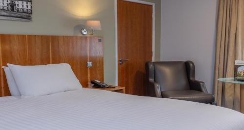 a hotel room with a bed and a chair at Cambridge Bar Hill Hotel, BW Signature Collection in Cambridge
