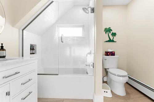 a white bathroom with a shower and a toilet at Whalers Rest A Bright and Historic 2BR Flat in Stonington Borough in Stonington