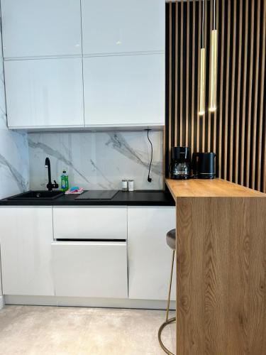 a kitchen with white cabinets and a sink at Balticus Apartamenty Standard Promenada Gwiazd 14 in Międzyzdroje