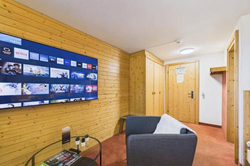 a room with a couch and a tv on a wall at Central suite to stay for 2 experience Saas-Fee in Saas-Fee
