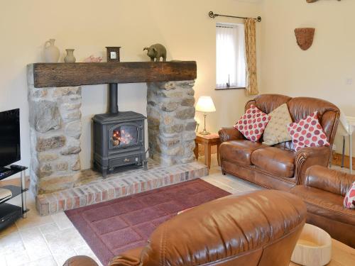 a living room with a fireplace and leather furniture at Gell Cottage in Criccieth