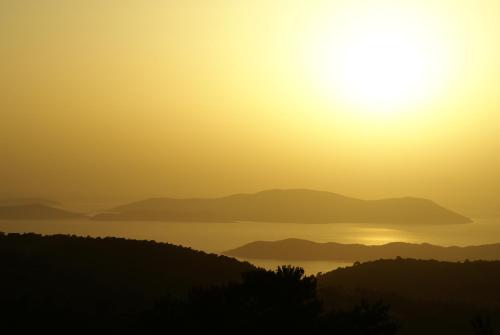 a sunset over a lake with mountains in the background at O Ioannis in Kritinía
