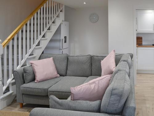 a living room with a gray couch with pink pillows at Spring Tides in Beadnell