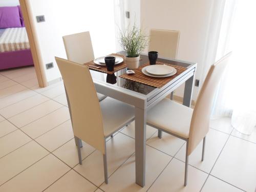 a dining room table with white chairs and a table at La trifula bianca apts. in Alba