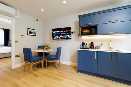 a kitchen with blue cabinets and a table and chairs at Club House Hotel Kilkenny in Kilkenny