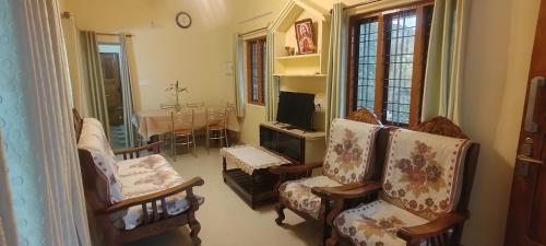 a living room with two chairs and a television at Skylark Homestay Panchalimedu in Pīrmed