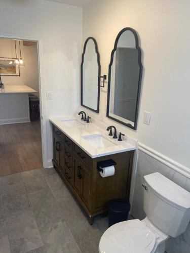 a bathroom with a toilet and a sink and mirrors at Comfy King Beds and Fast Wi-Fi near KC stadiums in Independence