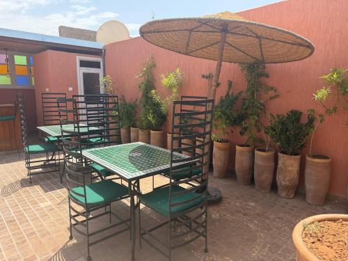a patio with tables and chairs and an umbrella at Riad Dihya in Marrakech